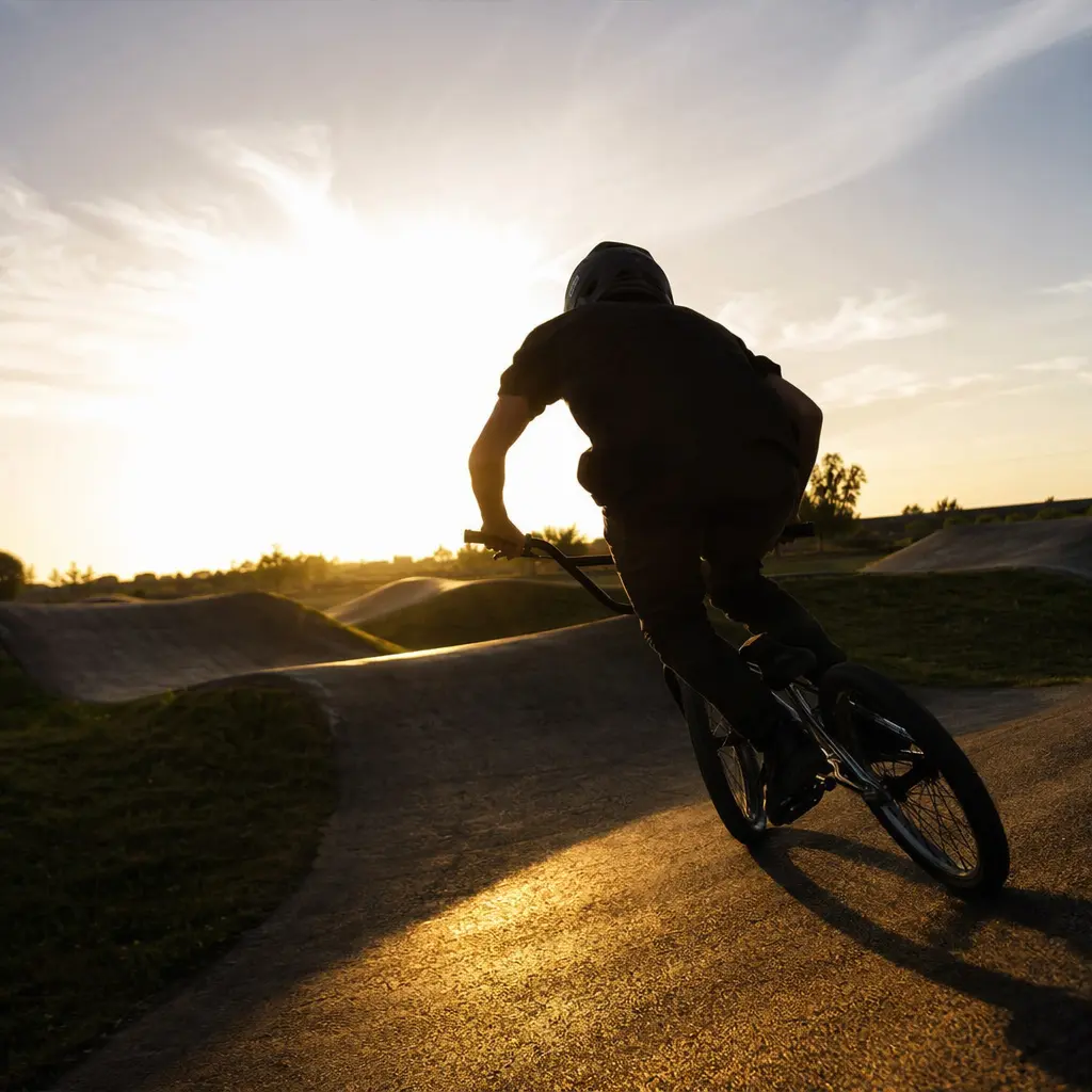 BMX bike being ridden on a pump track at golden hour, viewed from behind
