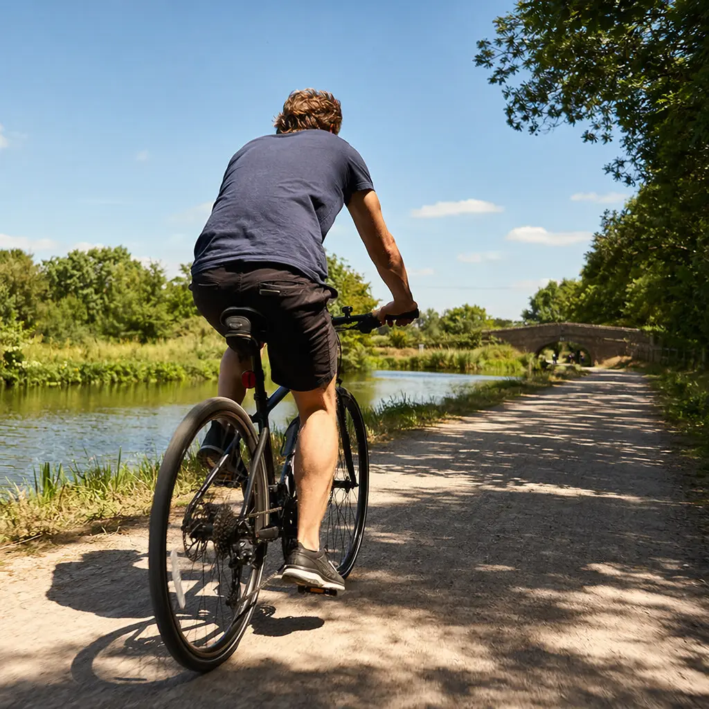 Hybrid bike being ridden along a sunny canal towpath