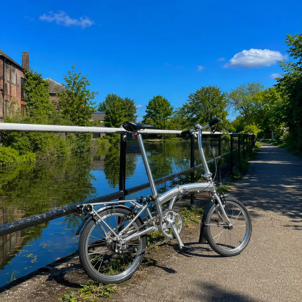 Folding bike beside a sunny canal towpath under a blue sky