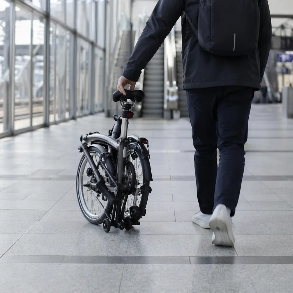 Folded bike being wheeled through a station concourse