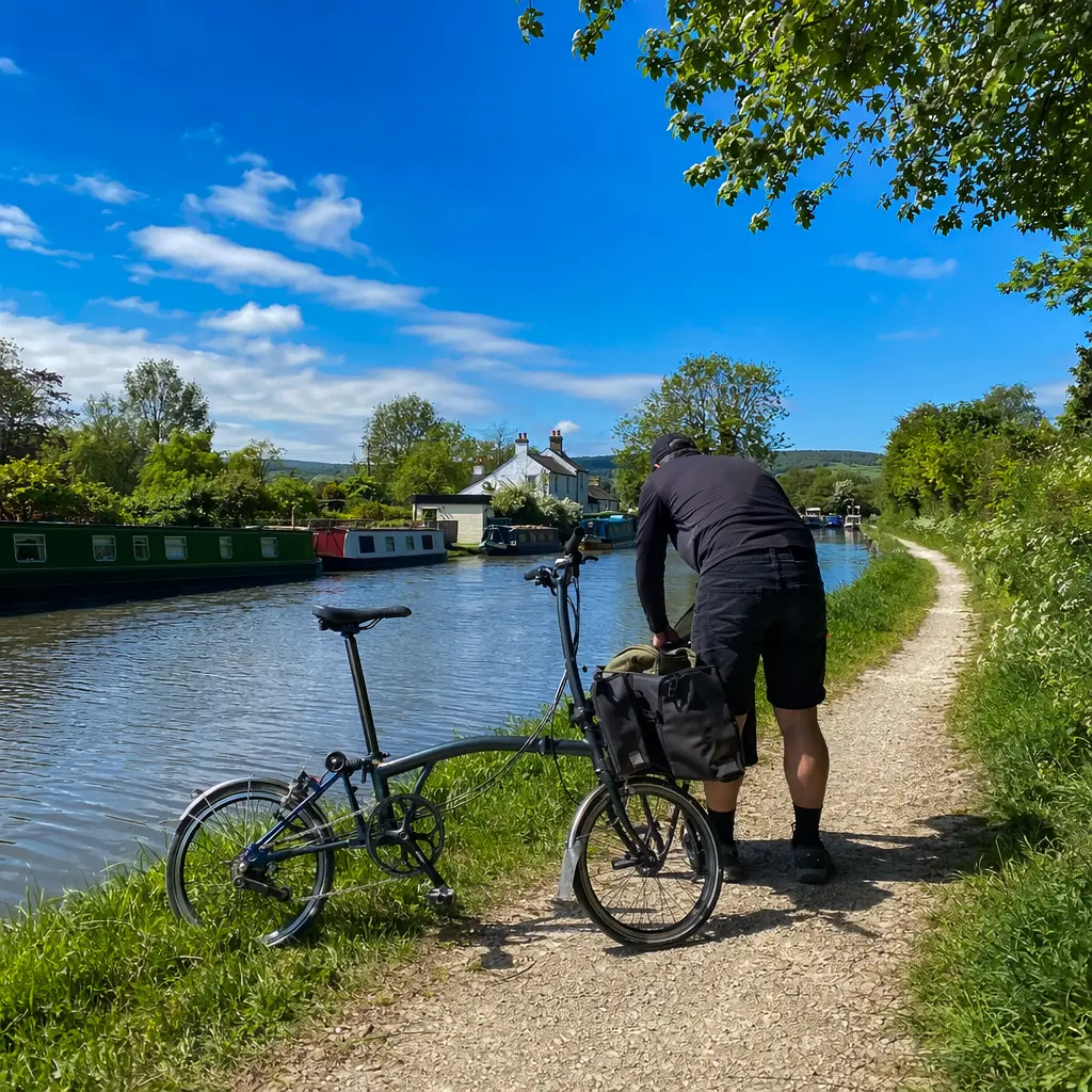 Folding bike beside a sunny canal towpath under a bright blue sky.